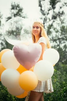 young girl with balloons on nature background.