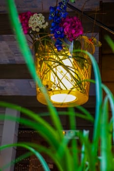 Flower decoration in cafe, Latvia. Flowers in a vase. Cafe interior with flowers. Flower vase decor hung at the ceiling. ..