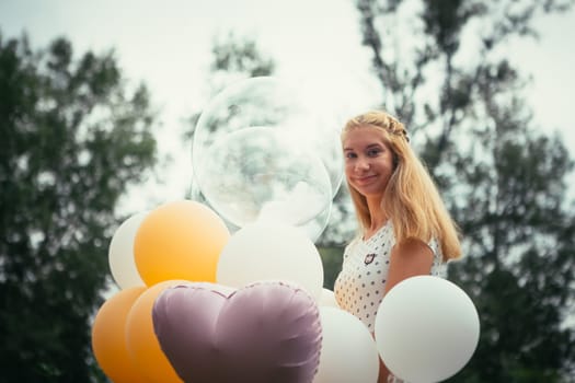young girl with balloons on nature background.