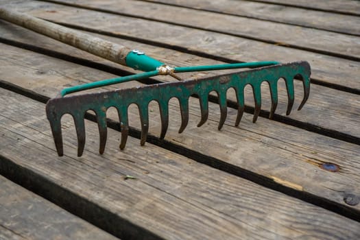 Old rake on the background of the wooden planks. Rake on the wooden plank floor.