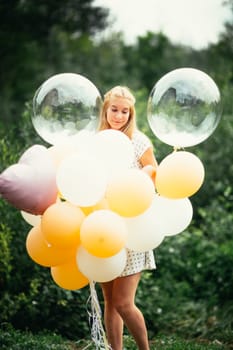 young girl with balloons on nature background.