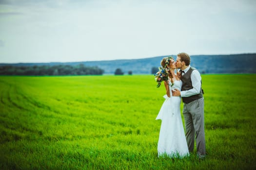 bride and groom stand on the background of the field.
