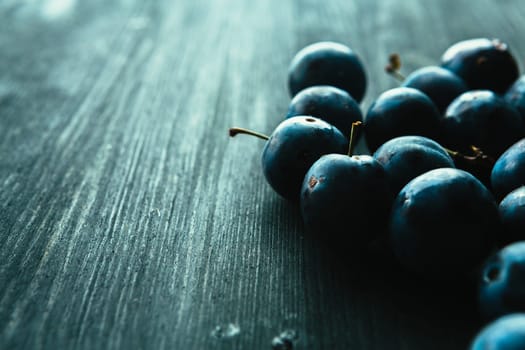 many fresh plums on black background close up.