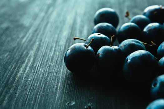 many fresh plums on black background close up.
