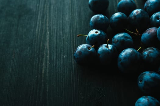 many fresh plums on black background close up.