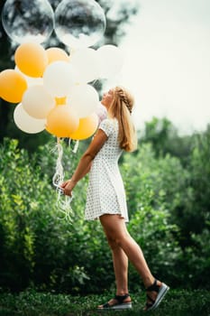 young girl with balloons on nature background.