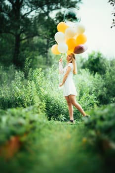 young girl with balloons on nature background.