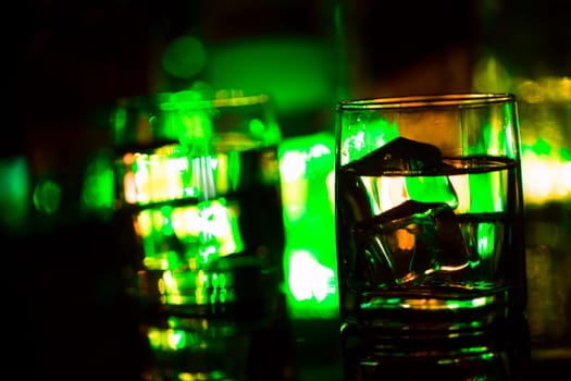colored lighting of glasses in the night club bar.