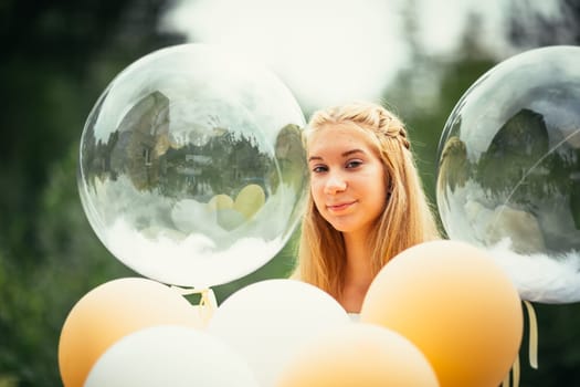 portrait of young girl with balloons on nature background.