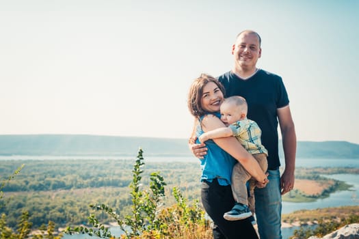 Happy family with baby son on nature background.