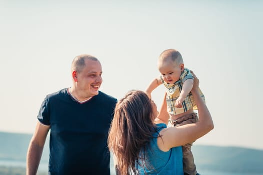 Happy family with baby son on nature background.