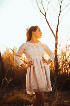 Beautiful girl standing in a field on a sunset background.