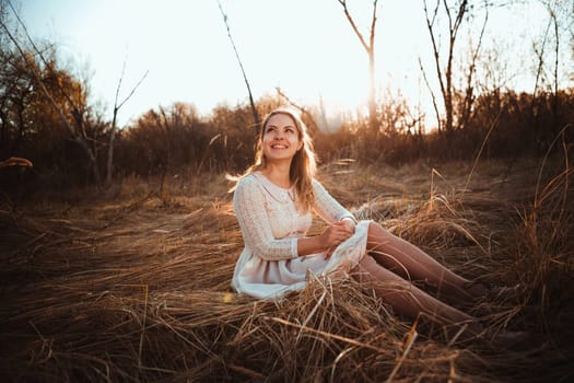 girl is sitting in the field on the sunset background.