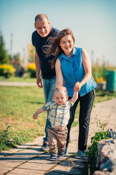 Happy family with baby son on nature background.