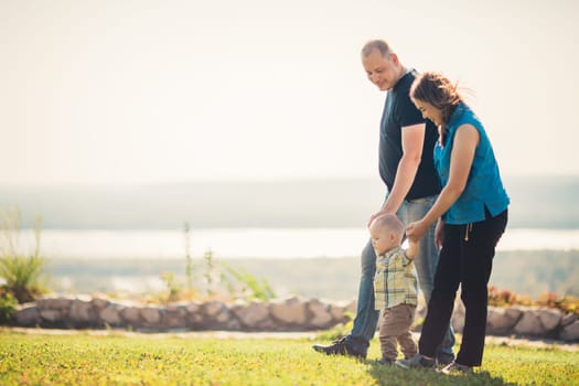 Happy family with baby on green grass.
