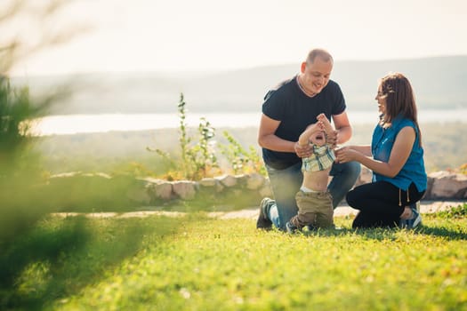Happy family with baby on green grass.
