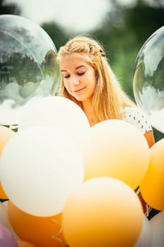 portrait of young girl with balloons on nature background.