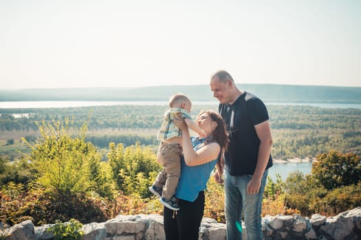 Happy family with baby son on nature background.