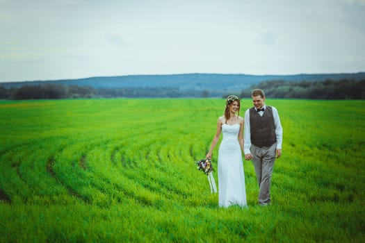 bride and groom stand on the background of the field.