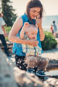 happy mother and toddler son near the fountain.