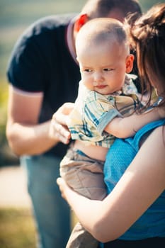 Happy family with baby son on nature background.