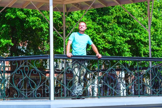 Young man stands in a gazebo and looks into the distance