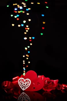 Decorative heart and red roses on a black background with heart-shaped bokeh . Valentine's Day card with copy space. Design element for romantic greeting card, wedding invitation