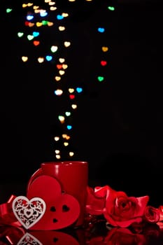 Still life: Cup of coffee, red heart and roses on black background with heart-shaped bokeh. Copy space. Valentine's Day setting table. Design element for romantic greeting card, festive menu of cafe