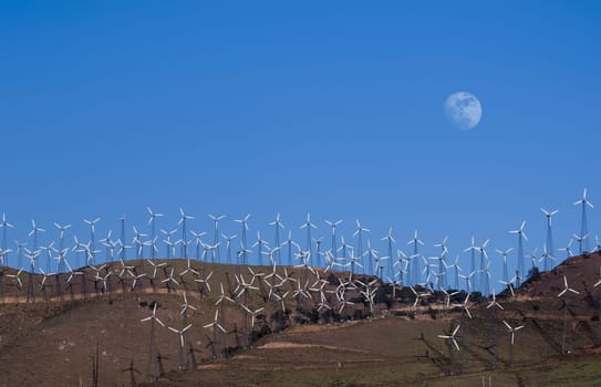Tehachapi, California, USA - June 12, 2011: Wind farms in wind power generation. Mechanical energy being transformed into electrical energy, with the beautiful moon in the background.
