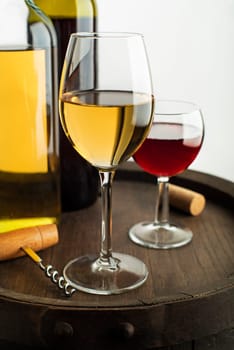 Glass and bottle of red wine and white wine on wooden barrel