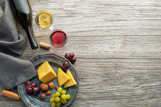 Glass and bottle of red and white wine with food snack on wooden background
