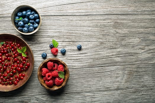 Mix of fresh berries in a bowl on wooden background