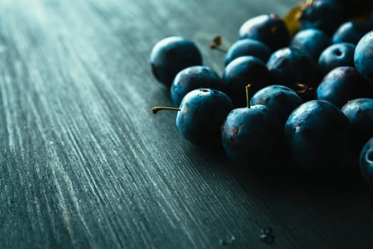 many fresh plums on black background close up.