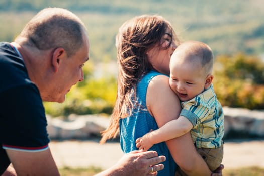 Happy family with baby son on nature background.