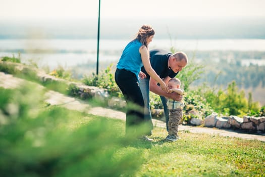 Happy family with baby son on nature background.