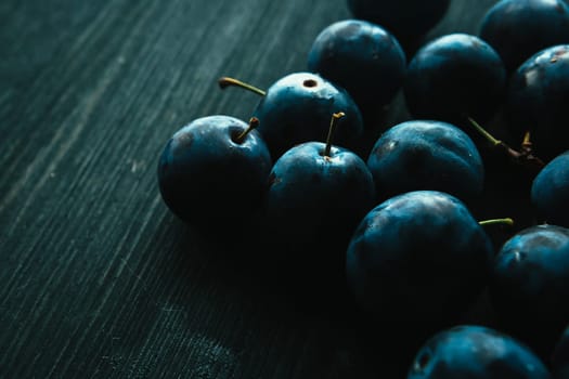 many fresh plums on black background close up.