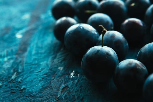 many fresh plums on blue background close up.