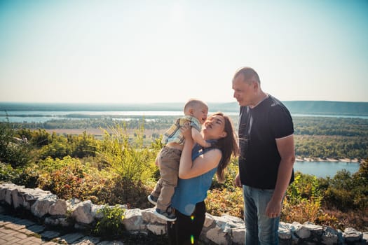 Happy family with baby son on nature background.