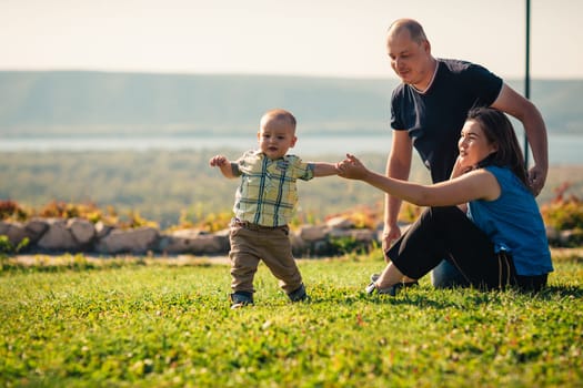 Happy family with baby on green grass.