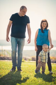 Happy family with baby on green grass.