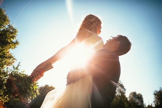 Dancing young bride and groom sunlight background.