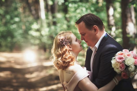 bride and groom on the background of trees and forest sun.
