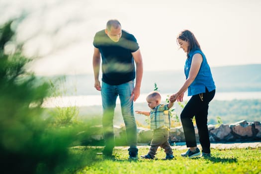 Happy family with baby on green grass.
