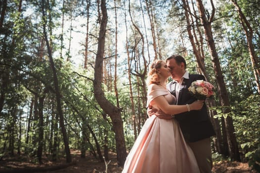 bride and groom on the background of trees and woods in full growth.