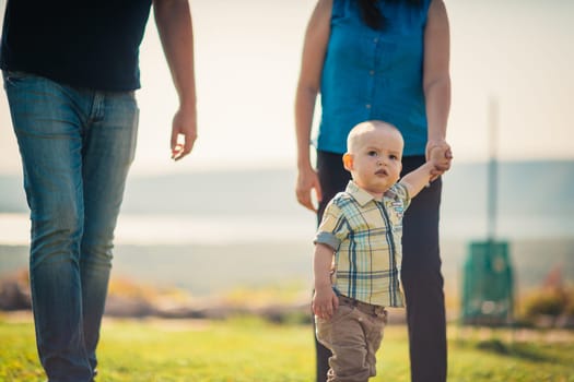 Happy family with baby on green grass.