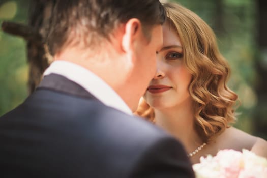 bride and groom kiss on the background of trees and forest.
