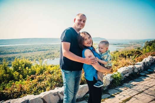 Happy family with baby son on nature background.