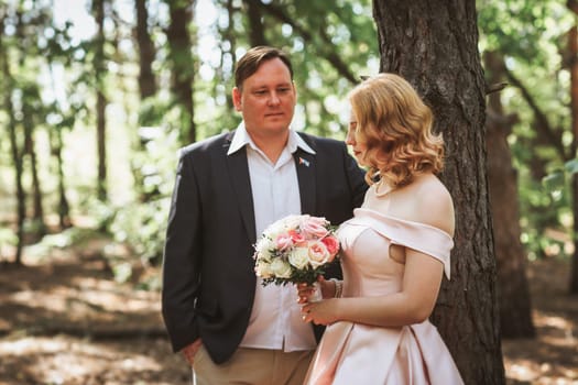 bride and groom kiss on the background of trees and forest.