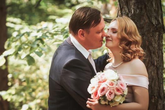 bride and groom kiss on the background of trees and forest.