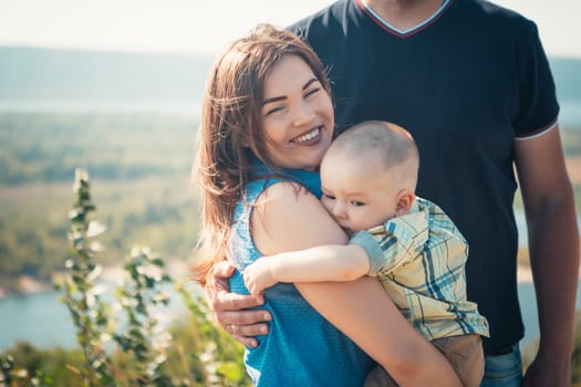 Happy family with baby son on nature background.